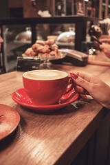 A girl is relaxing in a cafe, drinking coffee at the bar.
