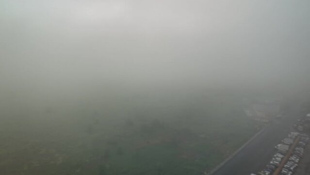This video shows a foggy view from an airplane window over a city and waterway. The thick fog obscures the details of the landscape below.