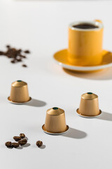 Coffee capsules with a cup and saucer in the background