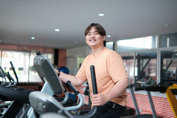 Overweight man smiling while exercising on elliptical