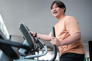 Overweight man smiling while exercising on elliptical