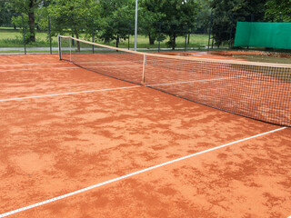 Wet clay tennis court with puddles during the rain. Outdoor tennis season. Spring rain on courts....