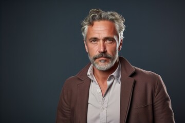 Fototapeta premium A man with a beard and gray hair is wearing a brown jacket and a white shirt