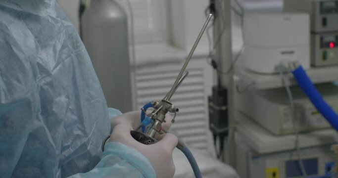 A veterinary surgeon prepares equipment for endoscopic surgery. The hands of a veterinary surgeon hold an endoscopic instrument in surgery and prepare to start the operation.