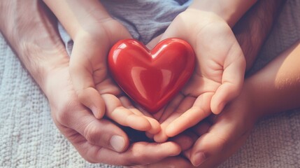 Obraz premium Adult and child hands holding red heart for world heart day