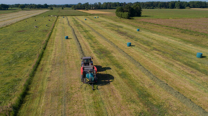 Treker oder Traktor mit einer roten Stroh Festkammerpresse bei der Strohernte auf einem gemähten Feld © vschlichting