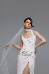 Woman in a white wedding dress on a gray background. The bride chooses a dress. Concept for a collection of modern and comfortable wedding dresses.