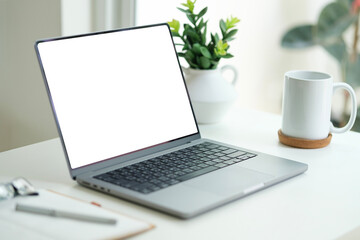 Laptop, coffee cup and notebook on white table. Empty screen for your advertise design.