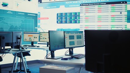 Empty work cubicles inside the enterprise headquarters office, business organization dealing with project planning and global expansion. Big data presented on a screen in coworking space. Camera B.