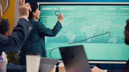 Office administrator presenting data reports and funding on interactive board, deliberating on income analysis with her associates. Accomplishing enterprise financial objectives. Camera A.