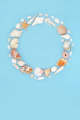 Shell wreath summer decoration with a collection of assorted seashells on blue background. Circular...