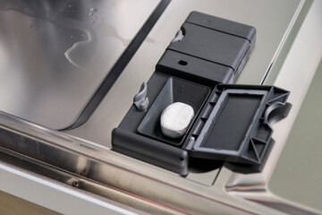 Open container, compartment of a dishwashing machine close up. Dishwasher tablet in a plastic dishwashing container, close-up