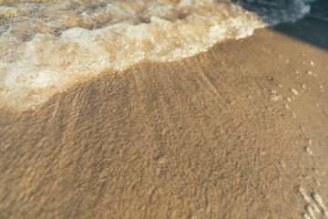 Foamy waves washing up on a sandy shore.
