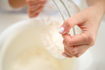 Closeup of female hands mixing ingredients in a bowl in the kitchen. Process of cooking pecan pie in home kitchen for American Thanksgiving Day.