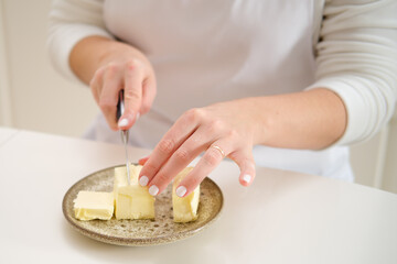 Closeup of woman's hands cutting butter on plate with knife. Process of cooking pecan pie in home kitchen for American Thanksgiving Day.