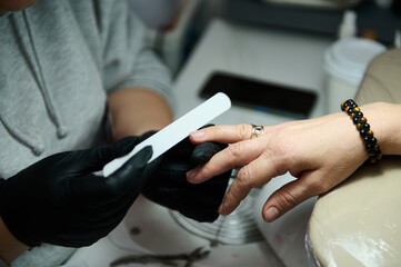 Manicure service in a beauty salon with black gloves