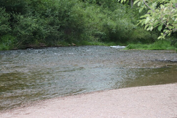 Waterfall stream close-up view from above clear flowing stream over ground gravel and stones. High quality photo