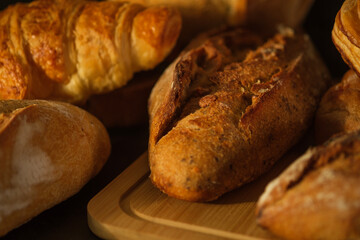 Fresh loaf of rustic traditional bread with wheat grain ear on wooden table.