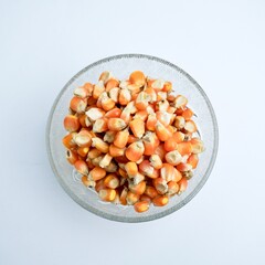 Groups of dry yellow corns in glass bowl food ingredients photography isolated on above top angle view horizontal ratio white background.