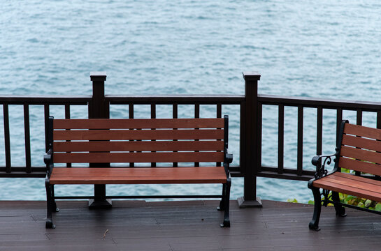 View of the empty bench and fence against the sea