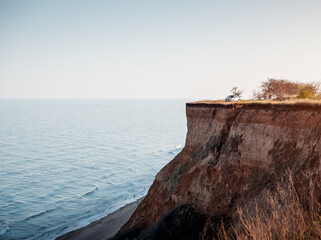 Silver car parked on top of a cllif by the sea at sunset. Cliffed coast of Black Sea, sandy ground...
