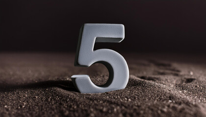 Number 5 made of gray stone isolated with shadow over dark sand.