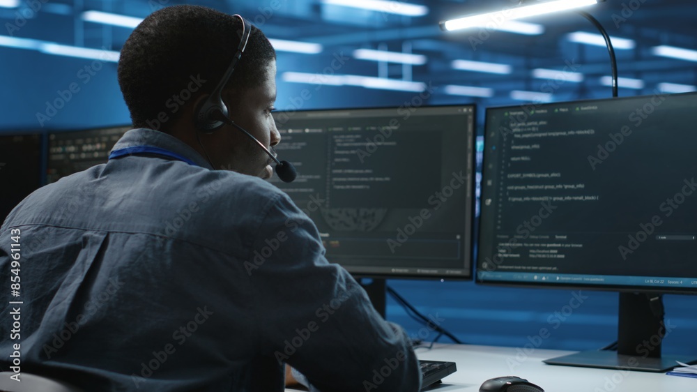 Poster it support worker in data center talking in headset mic with coworkers, coding on computer. man disc