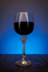 A beautiful glass of red wine surrounded by smoke. Glass with wine on a wooden surface.