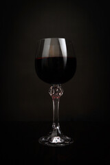 A glass of red wine in dark background