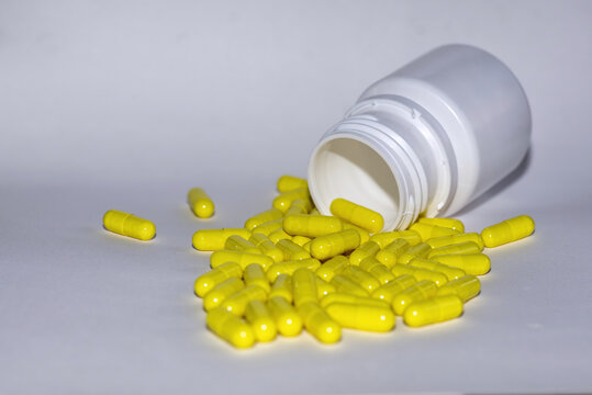    C&aacute;psulas amarillas derramadas de un frasco de medicamentos, representando temas de salud, medicaci&oacute;n y tratamiento. Ideal para ilustrar art&iacute;culos sobre cuidado de la salud con espacio para texto.