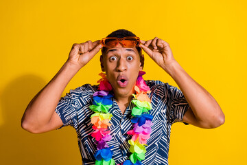 Photo of handsome impressed guy wear print shirt hawaii necklace handar dark glasses isolated yellow color background
