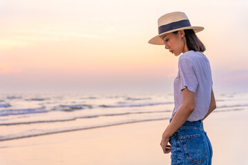Sadly and depressed asian woman standing with arms crossed on the beach near the sea alone. Bad feelings, through. Loneliness person. Depression Concept. Girl sit alone and think about her.