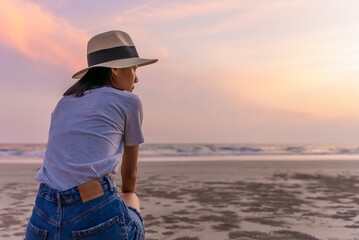 Sadly and depressed asian woman sitting on the beach near the sea alone. Bad feelings, through. Loneliness person. Depression Concept. Girl sit alone and think about her.