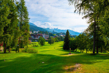 Village with House and Hotel with Panoramic View over Mountain with Clouds and Golf Course in a Sunny Summer Day in Crans Montana, Valais, Switzerland.