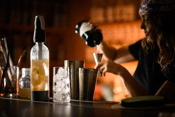 Siphon for making cocktails with a drink and a glass with ice cubes on the bar counter