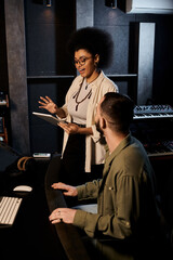 Two individuals from a music band engaging in a discussion within a recording studio setting.