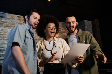 Fototapeta premium A music band gathered in a recording studio, attentively examining a sheet of paper.