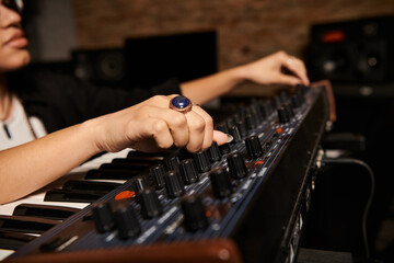 A person plays an electronic keyboard in a recording studio during a music band rehearsal.