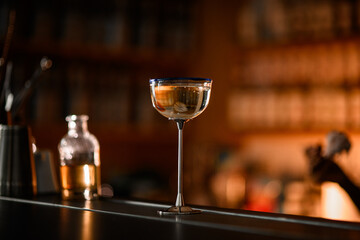 Cocktail glass with a tall metal stem standing on a bar counter