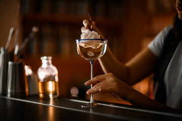 Bartender's female hands lower a piece of cotton candy into a glass