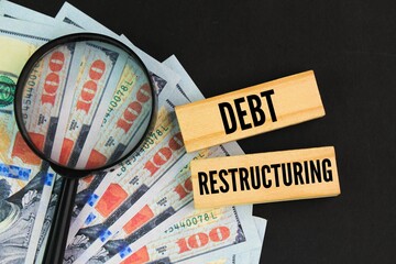 magnifying glass, dollar bill and stick with the word debt restructuring