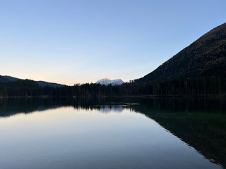 Lake Hintersee in Ramsau bei Berchtesgaden features crystal-clear waters reflecting the Bavarian Alps, surrounded by lush forests and rugged rocks—a serene, picturesque alpine escape.