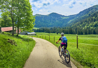 pretty senior woman riding her electric mountain bike on the mountains above Oberstaufen with...