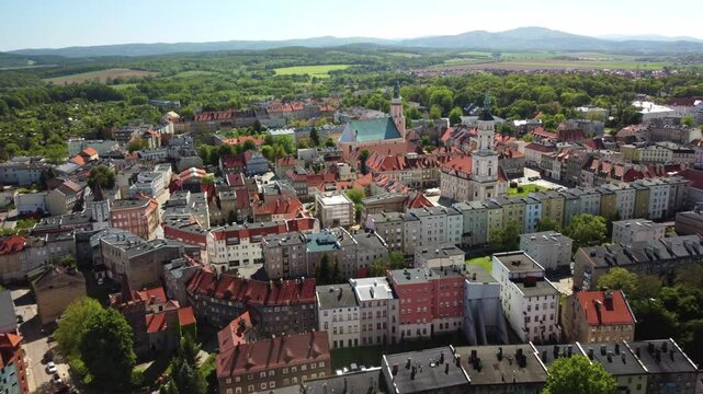 Historic buildings with red rooftops, lush greenery, and the surrounding scenic countryside with distant hills. Prudnik, Poland - Prudnik, Polska