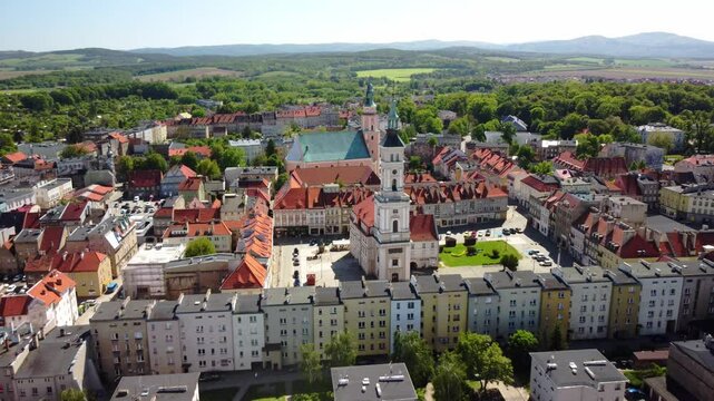 Prudnik town square, showcases the historic church and town hall amidst red-roofed buildings and lush greenery. Prudnik, Poland - Prudnik, Polska