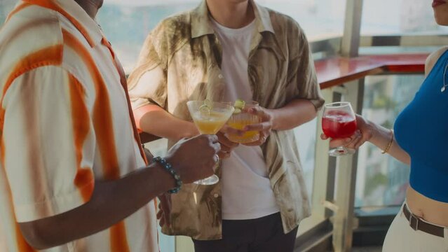 Cropped shot of unrecognizable group of people spending weekend together in trendy bar with refreshing cocktails