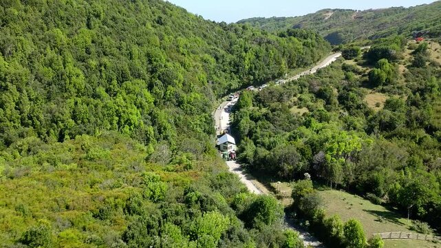 Aerial View Of Tractor Pulling Mobile House Across Road In Chiloe, Chile. This Is called Minga, A South America term meaning - coming together for the common good. Pull Back Shot