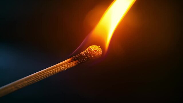 Lit matchstick with bright flame against a dark background.