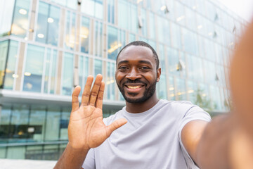 African American man with smartphone having video call on street in city. Guy blogger streaming chatting in social network. Man having virtual meeting vlog online chat outdoor Selfie webcamera view