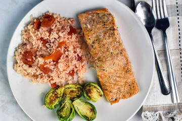 baked salmon served with rice and brussel sprouts,